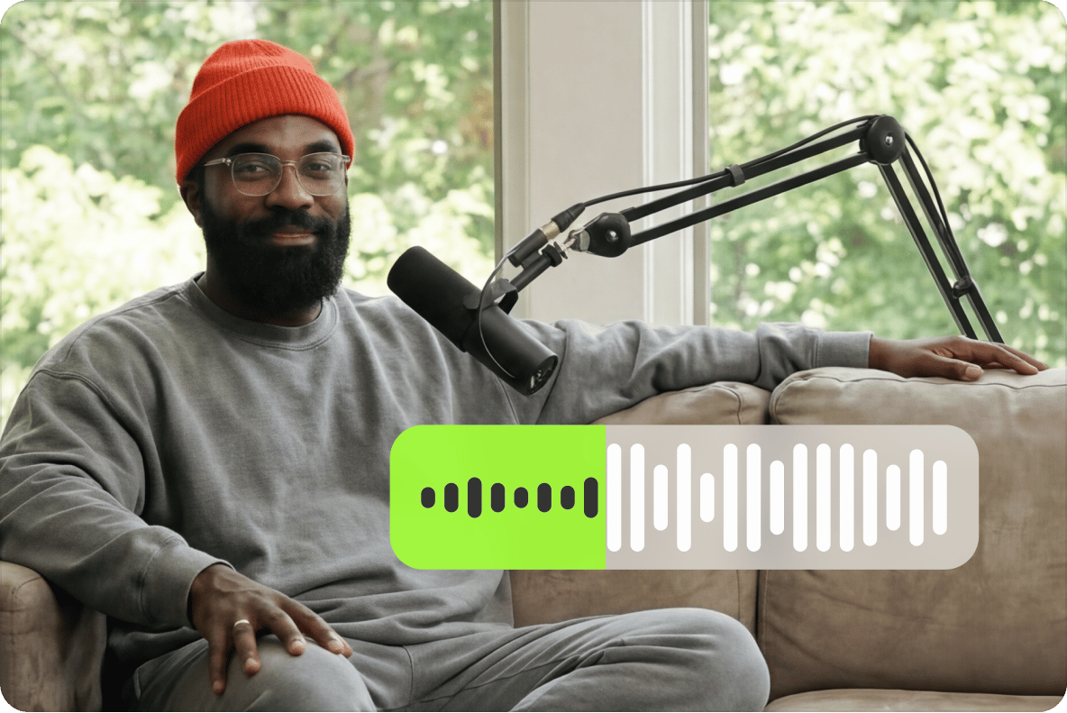Bearded man in an orange beanie sitting on a sofa with a studio microphone and an auto subtitles track panel.