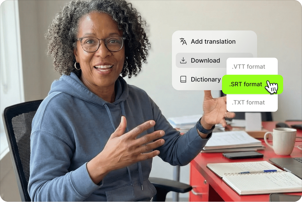Smiling woman gesturing at her desk with a cursor selecting the SRT subtitle format from a download translation menu.
