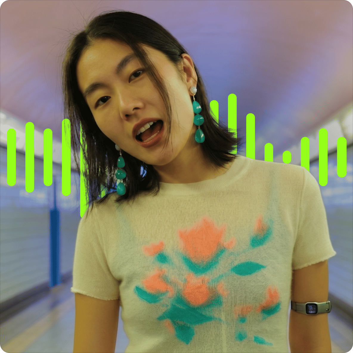 Woman with green dangling earrings singing in a tunnel with a bright green digital sound wave visual behind her.