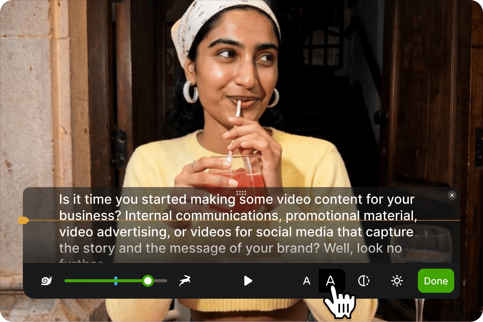 Teleprompter showing cursor adjusting text size over a video of a smiling woman in a yellow sweater sipping a red drink