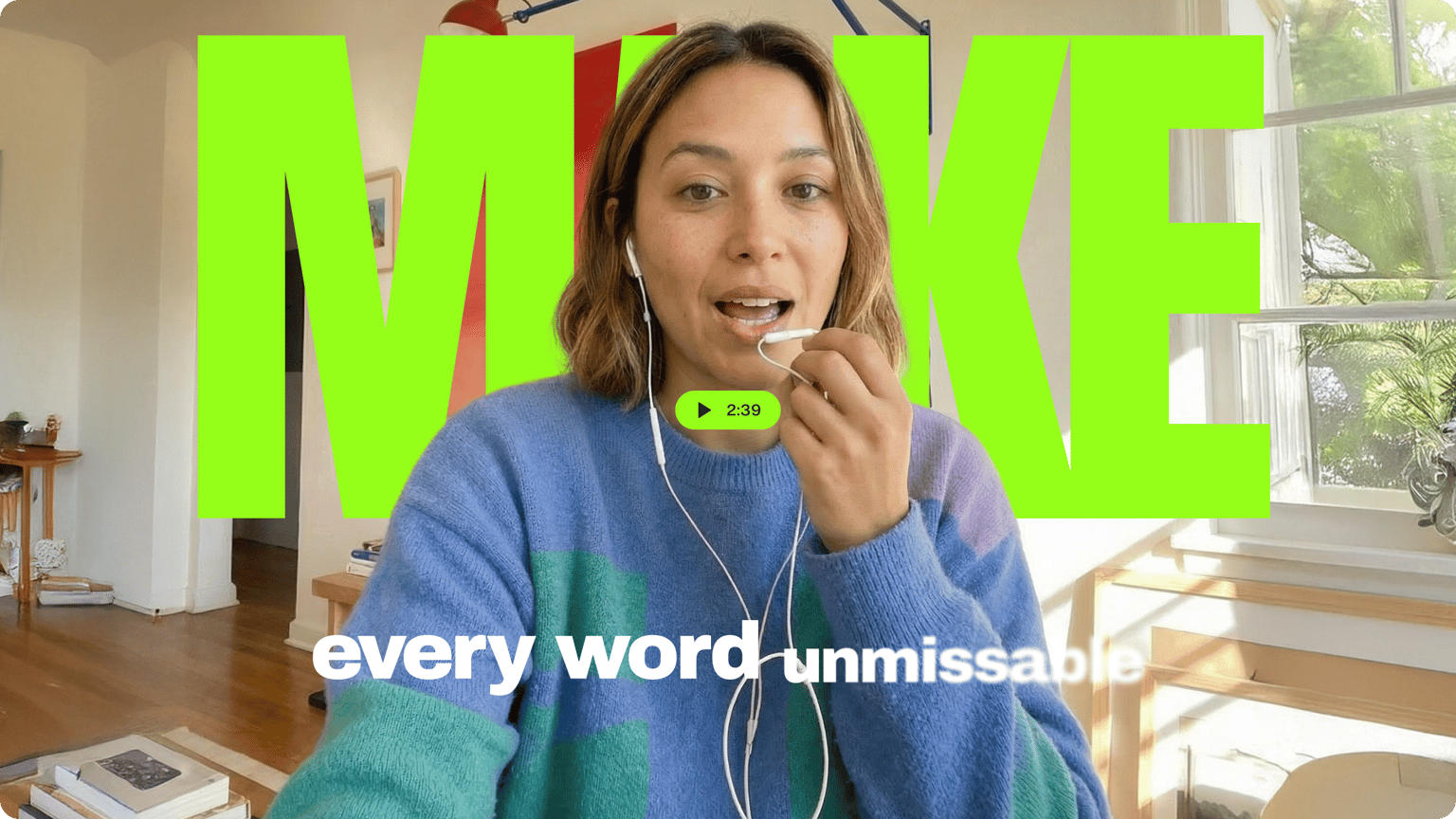 Woman in a blue sweater speaking into a microphone with large green animated text behind her saying make.