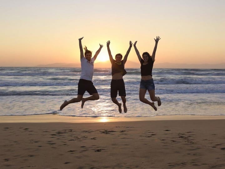 Unblurred photo of friends jumping on a beach at sunset