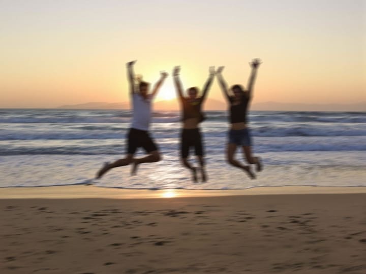 Blurry photo of friends jumping on a beach at sunset